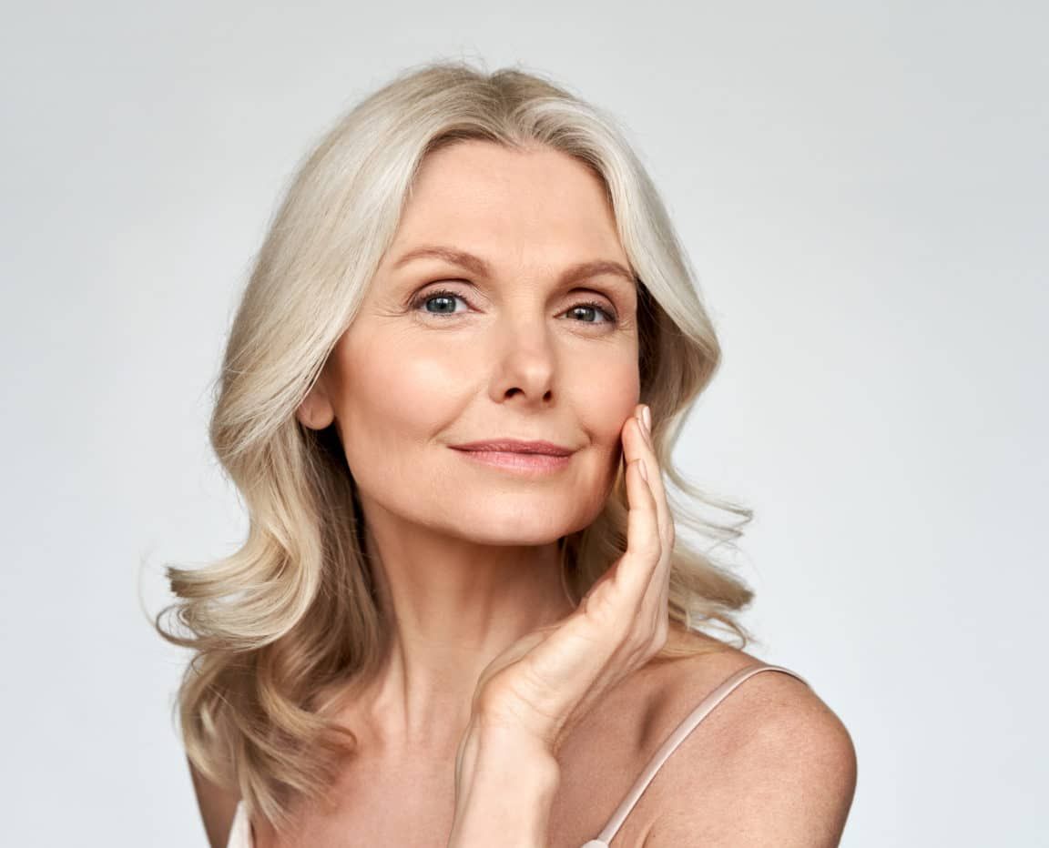 Elegant woman touching her face, smiling gently.
