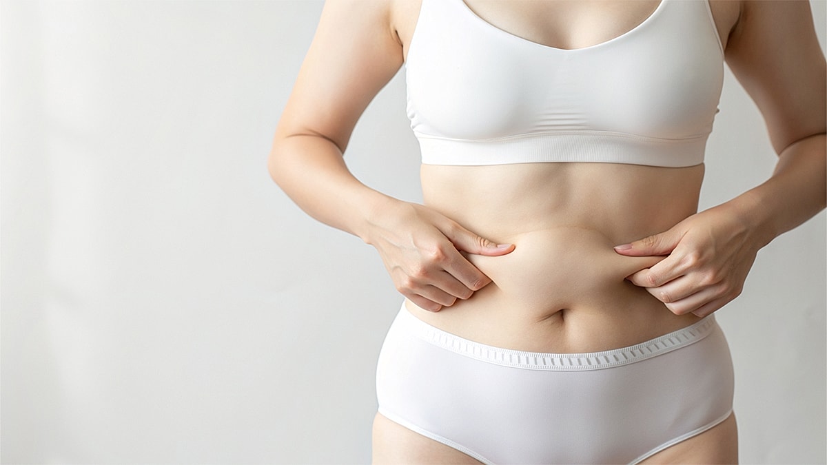 Woman in white underwear examining her abdomen.
