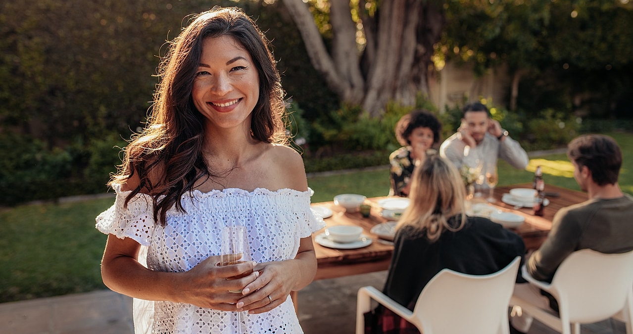 Woman smiling at outdoor gathering with friends.