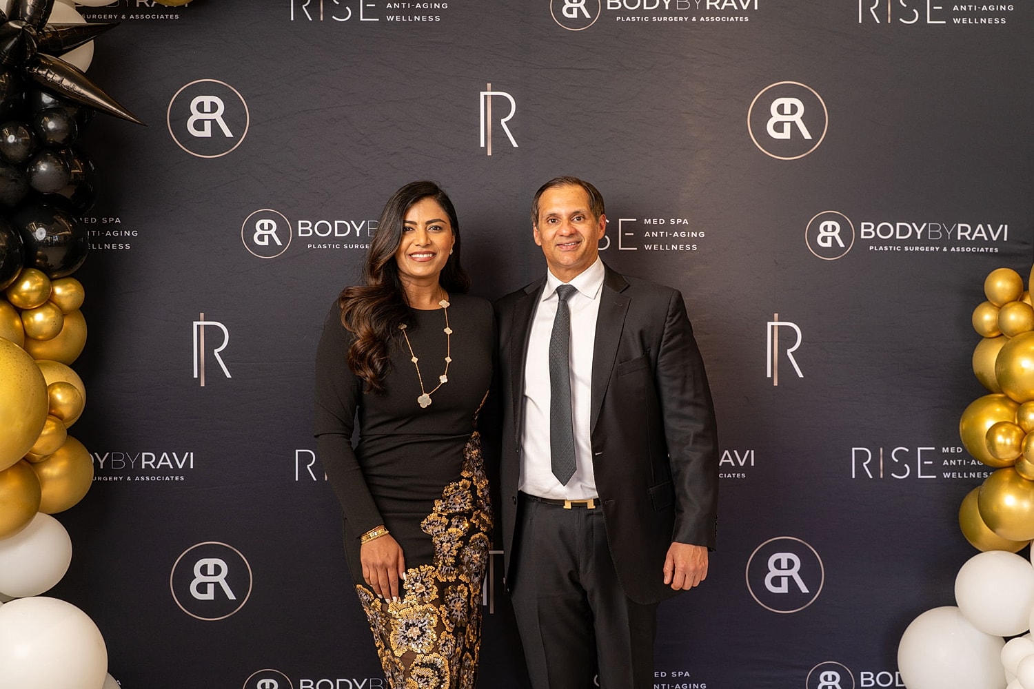 Couple posing at event with branding backdrop.
