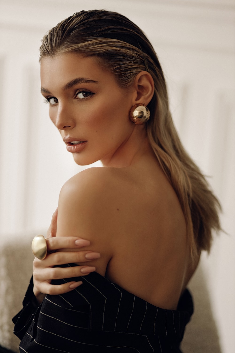 Elegant woman with gold accessories and sleek hair.