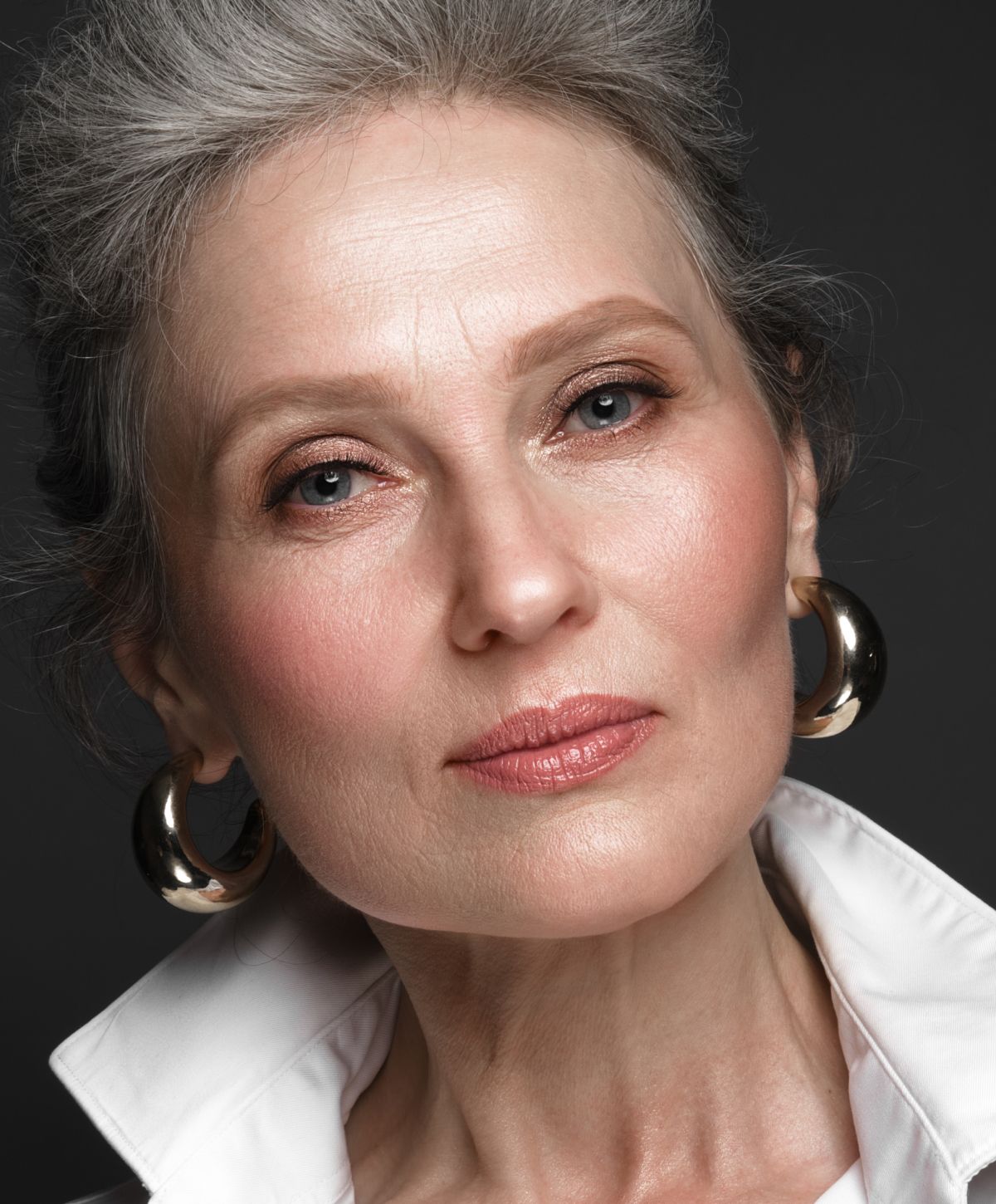 Close-up portrait of a mature woman with earrings.