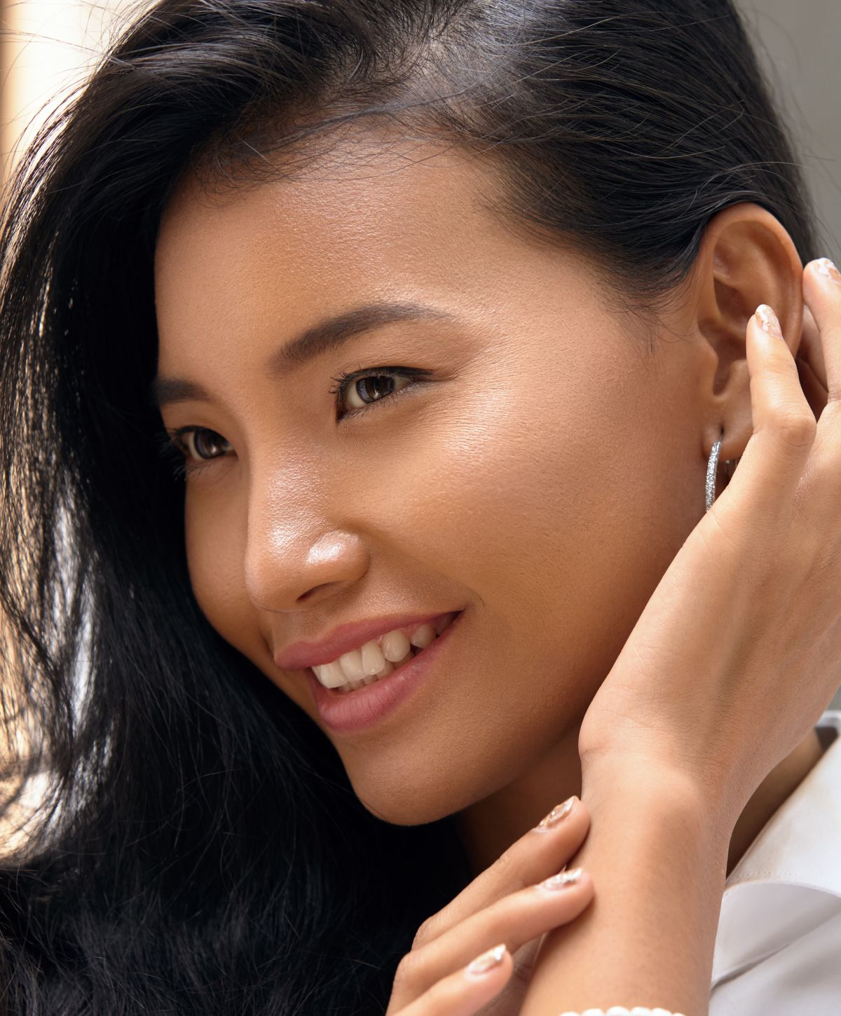 Smiling woman with long black hair and earrings.