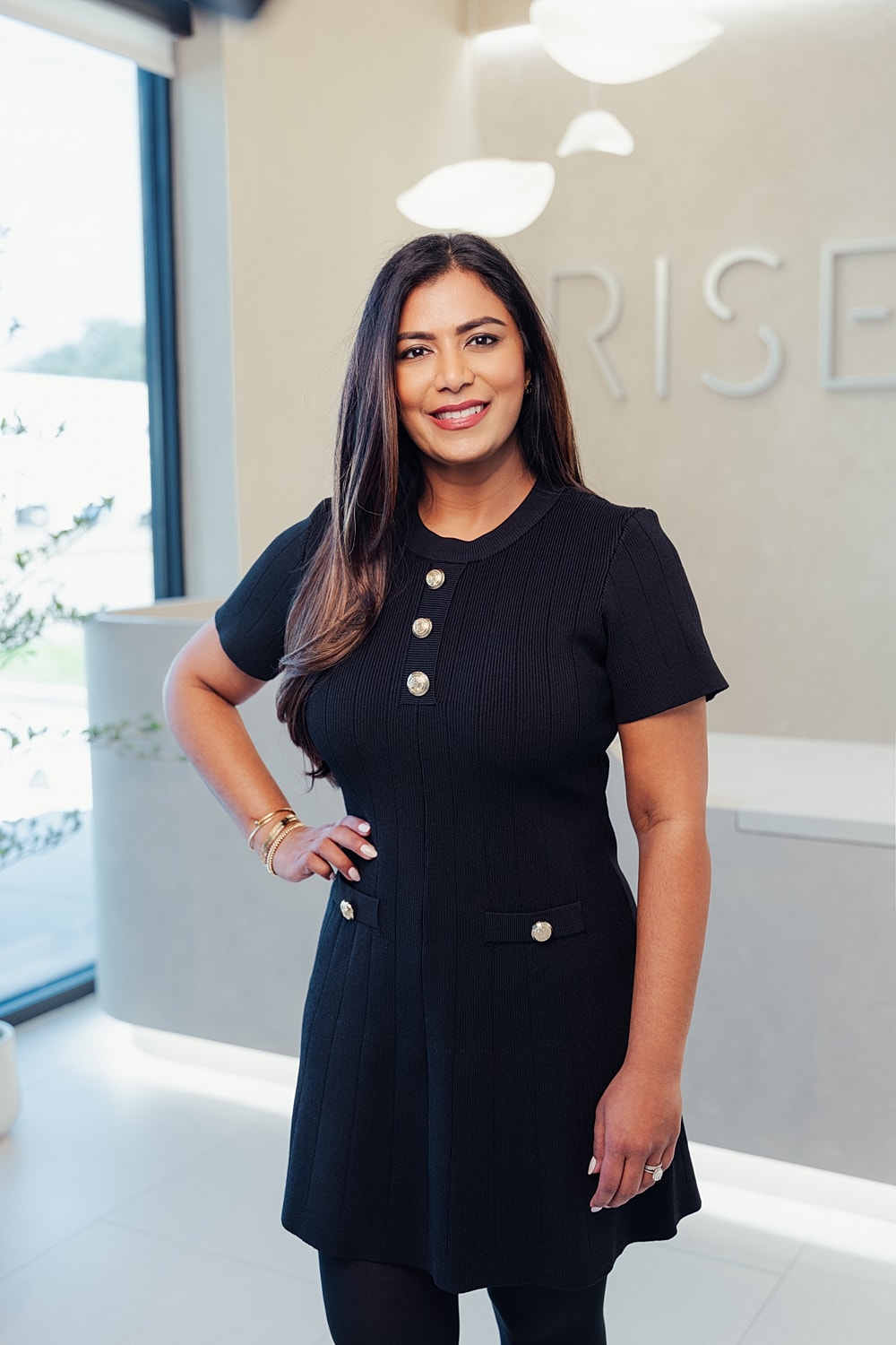 Smiling woman in black dress at modern office.