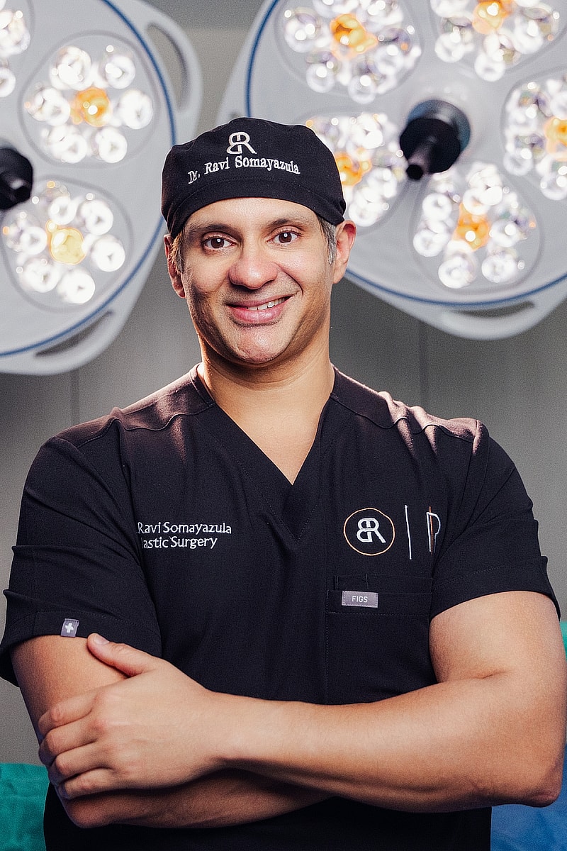 Surgeon smiling in operating room setting.