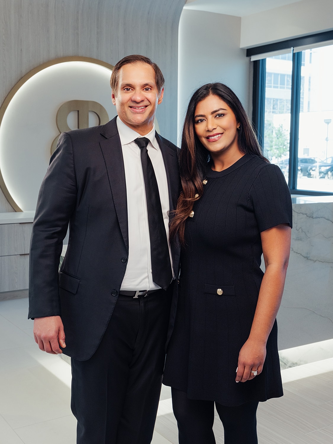 Professional couple posing in modern office setting.