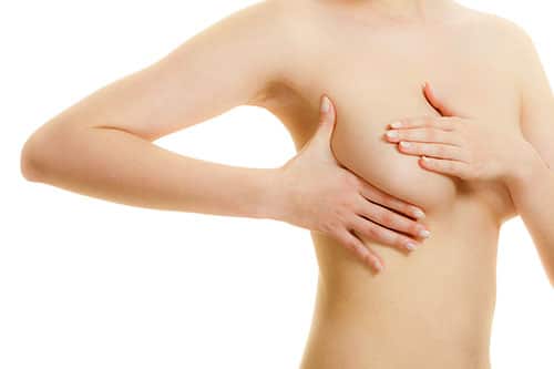 Health care medical concept. Young woman examining her breasts for lumps or signs of breast cancer isolated on white